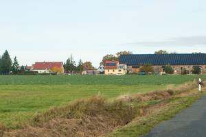 rechts im  Vordergrund die Straße nach Ottersburg, im Hintergrund der Ort mit einem großen Gebäude mit PV-Anlage