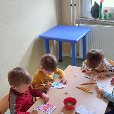 Zeichnende Kinder am Tisch mit Papier und Bundstiften