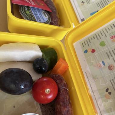 Eine Frühstücksbox gefüllt mit Obst und Gemüse, Vollkornbrot und Käse