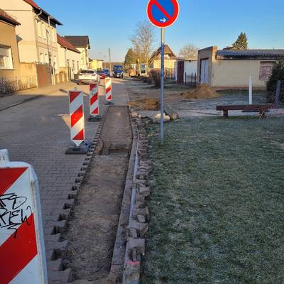 aufgenommenes Straßenpflaster  und Warnbaken bei der Reparatur der Regenentwässerung in Birkholz