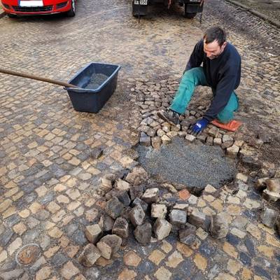 ein Mitarbeiter des Bauhofes repariert Fahrbahnschäden in der Blumenstraße - das Pflaster wurde aufgenommen und wird nun neu eingesetzt