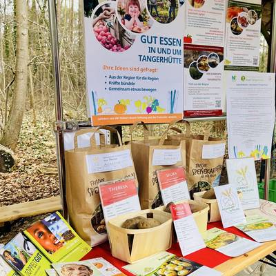 Tisch mit Papierbeuteln und frischen Kartoffeln dazu Informationsmaterial