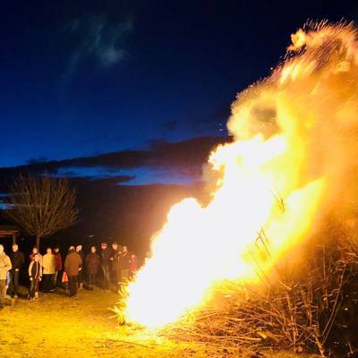 Menschengruppe steht um Osterfeuer herum