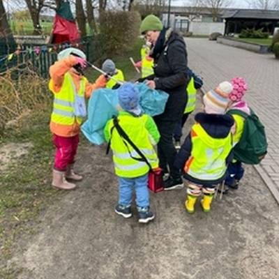 Sechs Kinder Sammeln gemeinsam mit Erzieherin Müll ein