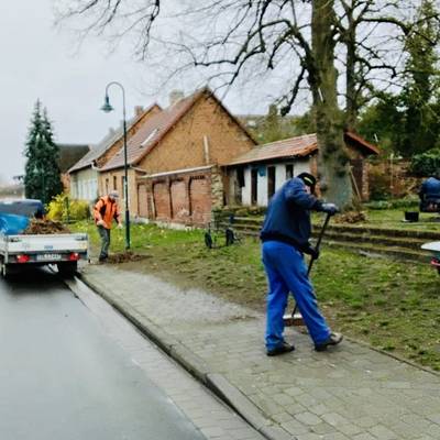 Der Gehweg wird mit einem Besen gefegt und der Schmutz wird auf ein Fahrzeug geladen