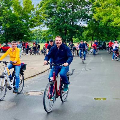 Mehrere Radfahrer sind auf dem Bild. Freudig wird sich auf dem Fahrrad fortbewegt. Einige nutzen die Chance zur Rast.