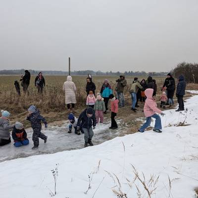 Die Kinder schlittern über eine vereiste Pfütze.