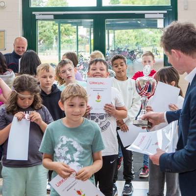 Bürgermeister überreicht Pokal und die Urkunden an die Kinder, die stolz Ihre Urtkunden hochhalten.