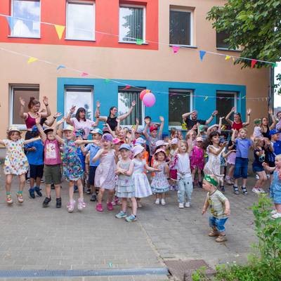 Die Kinder führen mit Ihren Erziehern einen Tanz auf und singen ein Lied und haben Spaß dabei.