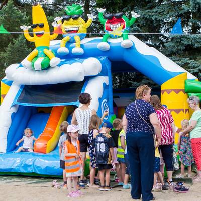 Kinder spielen ausgelassen auf einer großen blauen Hüpfburg, sie springen und rutschen unter den achtsamen Augen der Erwachsenen