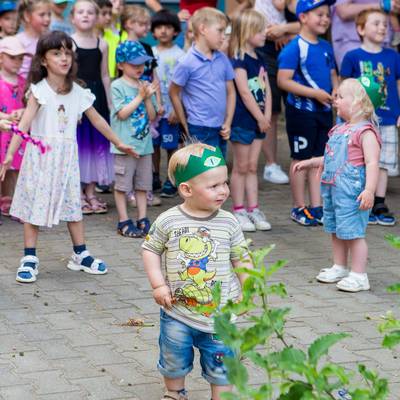 Die Kinder tanzen ausgelassen zur Musik, im Vordergrund steht ein kleiner Junge der sichtlich Spaß hat und seine ersten Tanzversuche unternimmt
